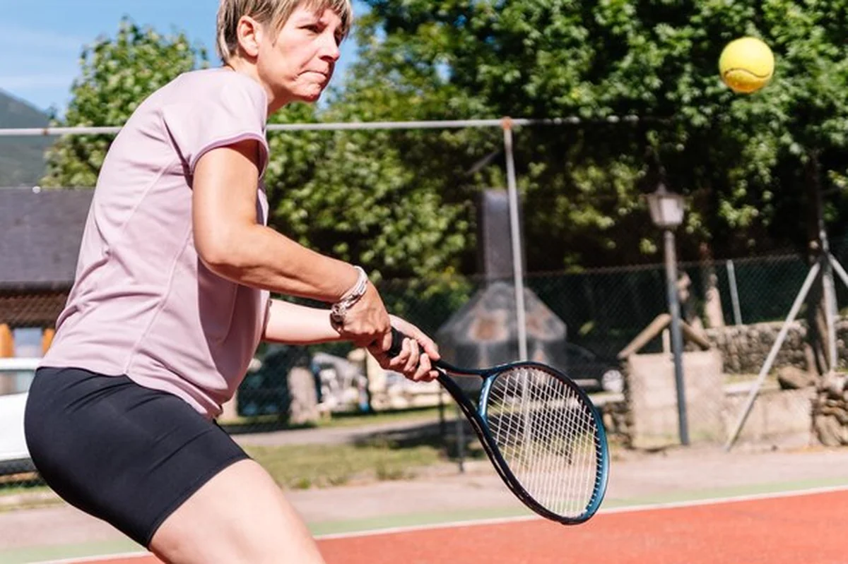 Kobieta tenisistka przygotowuje się do uderzenia piłki na kortu ziemnym