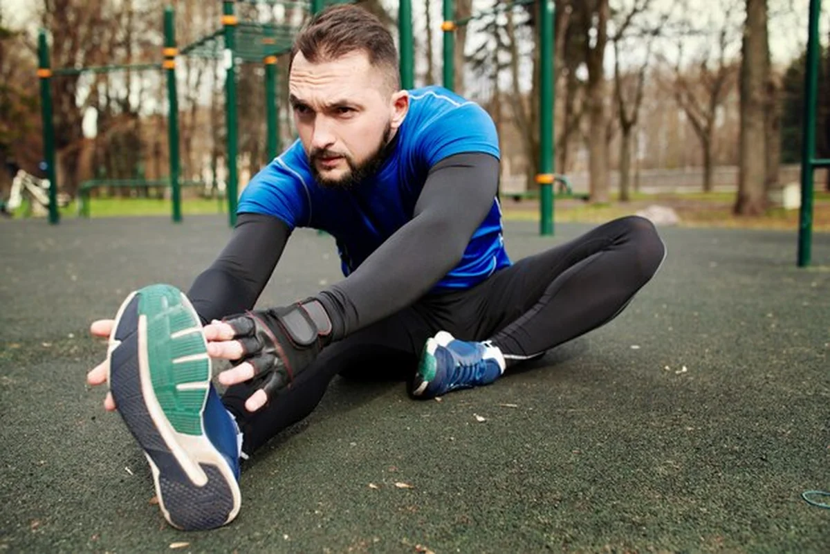 Młody siłacz rozciąga mięśnie przed treningiem